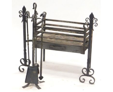 A wrought iron fire grate, the ends decorated with fleur de lis, and a four piece wrought iron companion set, with rams head 