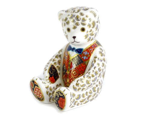 A Royal Crown Derby porcelain bear shaped paperweight, in the seated position wearing a bow tie, gold button, boxed.