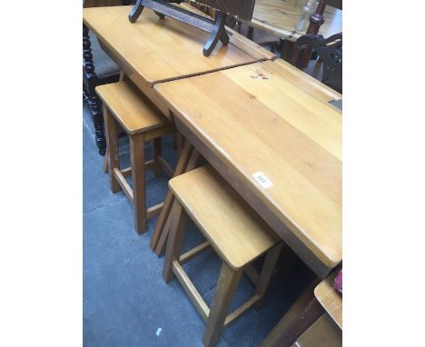 A pair of light wood school desks with stools. 