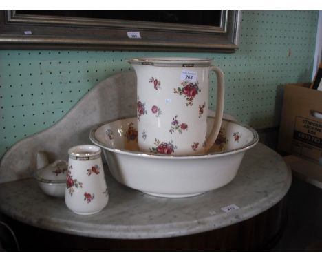 An early 20th century ceramic washbowl and jug, together with dressing table pot and vase, each decorated with pink floral sp