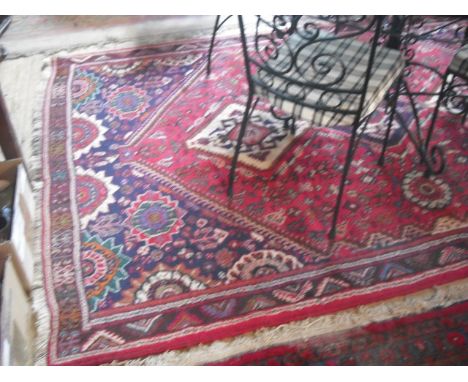 A 20th century woven carpet, having large central red lozenge with stylized floral decoration within a geometric repeating pa