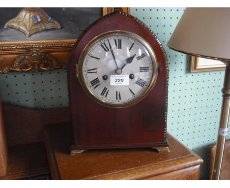 A 20th century mahogany oak arched shaped striking mantle clock, the dial bearing Roman numerals.