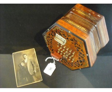 An early 20th century walnut cased hexagonal concertina, having inlaid brass decoration surrounding pierced fretwork to each 