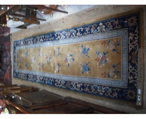A mid-20th century Chinese runner, having floral springs on a light ground surrounded by a repeating pattern on a blue ground
