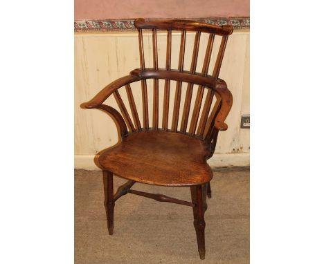 An early 19th century provincial elm and beech comb back Windsor chair, having a pronounced dish shaped seat on turned suppor