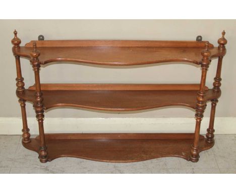 A Victorian mahogany serpentine front three-tier open hanging wall shelf, having ring turned supports, h.57cm, w.92cm, d.17.5