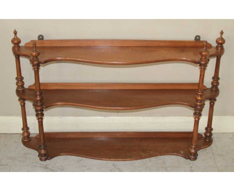 A Victorian mahogany serpentine front three-tier open hanging wall shelf, having ring turned supports, h.57cm, w.92cm, d.17.5