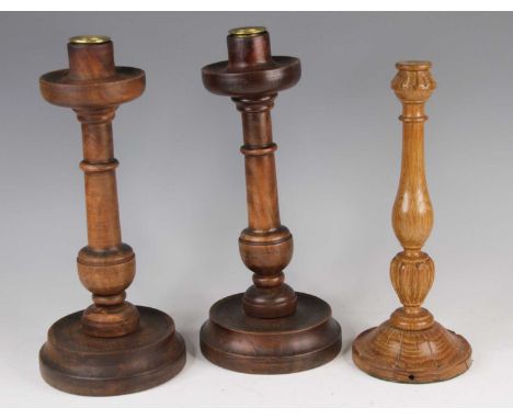 A pair of early 20th century turned walnut candlesticks, h.32cm; together with a further turned oak table lamp (lacking elect