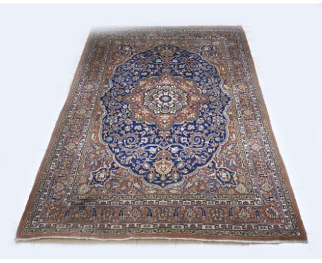 Hand-knotted Persian carpet, floral decorated. Red in colour, with a blue medallion in the middle. One tear on the side. Dime