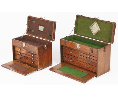 Two (2) small oak machinist chests with leather handles. Both feature shallow compartments on top and shallow drawers underne