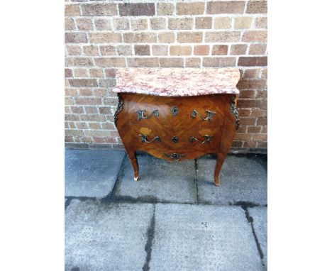 A CONTINENTAL COMMODE CHEST OF BOMBE OUTLINE  the shaped flecked marble top with two drawers under with gilt mounts and raise