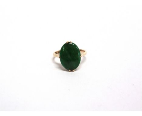 A JADE PANEL RING  stamped 14K and other indistinct marks, the oval shallow cabochon claw set, finger size M, 2.7g gross