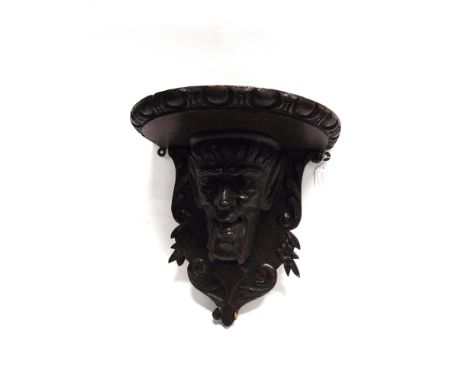 A CARVED OAK FIGURAL WALL BRACKET  modelled as a Satyr, the semicircular top 38cm wide 40cm high overall