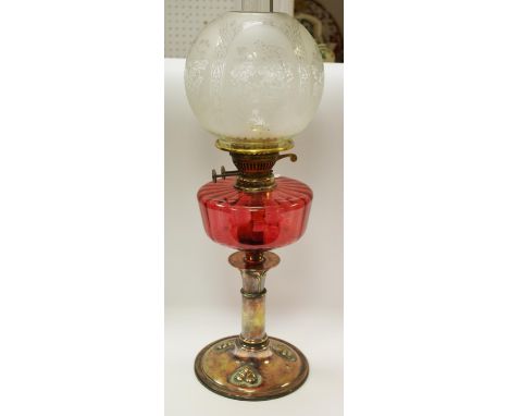 An Art Nouveaux oil lamp, red glass reservoir, etched dome