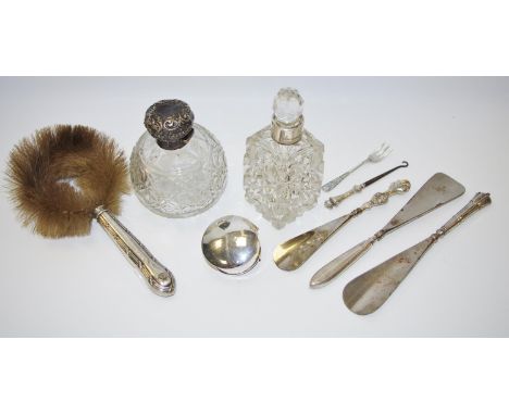 Three silver hafted shoehorns and a button hook; two silver mounted perfume bottles; a crescent shaped silver brooch; a silve