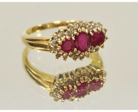 A 9ct gold ring set with a central oval ruby flanked by two round rubies and surrounded by diamonds, 3g gross