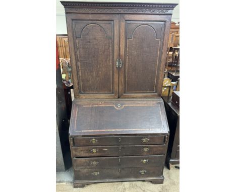 An 18th century oak and mahogany bureau bookcase, with a moulded dentil cornice above a pair of cupboard doors enclosing shel