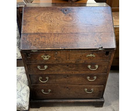 An 18th century oak bureau with a sloping fall enclosing a fitted interior and central well above two short dummy drawers and
