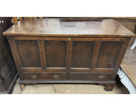 An 18th century oak coffer with a planked rectangular top above a panelled front and drawers on bracket feet 