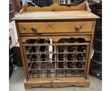 A pine wine rack / side cabinet with a frieze drawer and pull out wine rack on a bracket feet 
