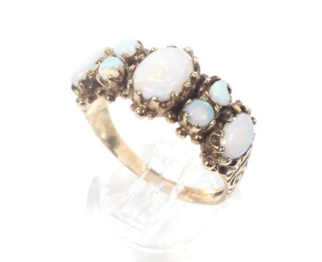 A vintage 9ct gold and opal dress ring in Victorian style. The three graduated oval cabochon white opals spaced by pair of sm