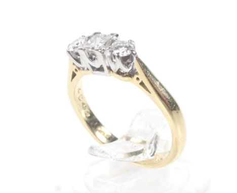 A modern 18ct gold and diamond three stone ring. Centred with a princess-cut diamond between round brilliants, all claw set i