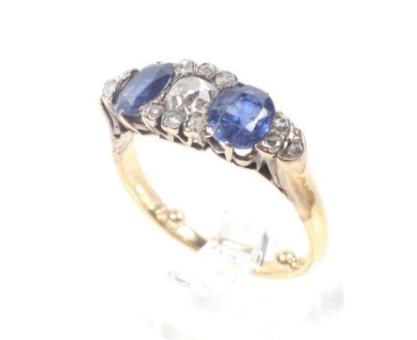 A late Victorian gold, sapphire and diamond dress ring. Centred with a cushion shaped old-cut diamond approx. 0.38cts, betwee