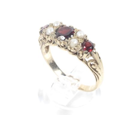 A vintage 9ct gold, garnet and half-pearl dress ring in Victorian style. The three graduated round mixed-cut garnets spaced b