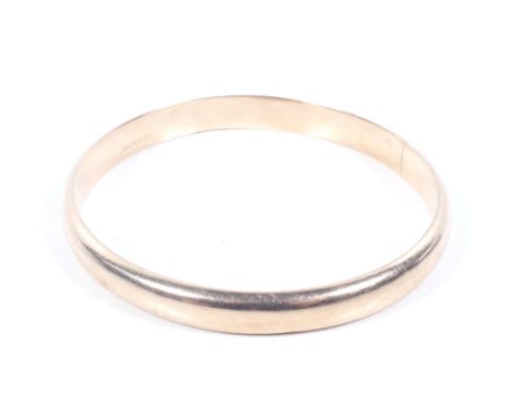 An early 20th century rose gold hollow-domed slave bangle. Stamped '9ct', 8.5mm wide, 10.7g