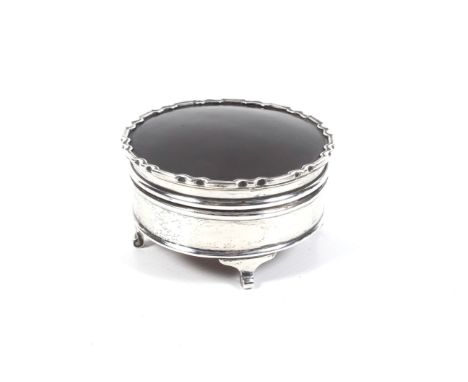 A silver and tortoiseshell mounted round trinket box. The hinged lid inset with a tortoiseshell panel within shaped moulded b