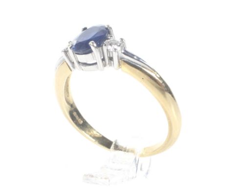 A modern 18ct gold, sapphire and diamond three stone ring. Centred with a oval mixed-cut sapphire between round brilliant dia