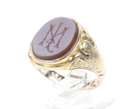 A Victorian 15ct gold and sard onyx oval signet ring. The stone engraved with a monogram, rub-over set between floral engrave