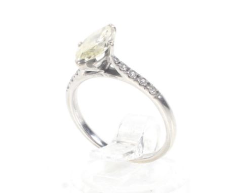 A modern marquise diamond solitaire ring with small diamond shoulders. The marquise diamond claw set in white between small g