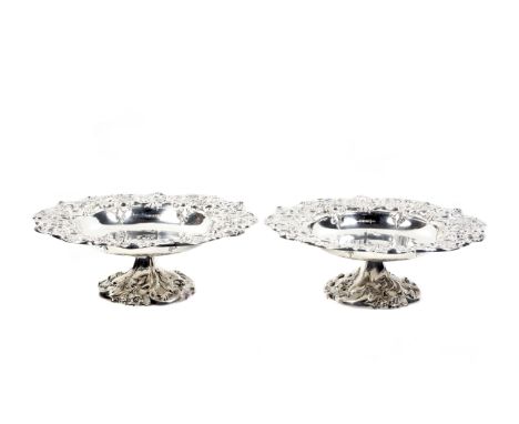 A pair of silver pedestal fruit dishes or tazzas. Each with a broad border and domed foot, finely chased and embossed with el