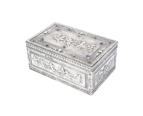 An early 20th century silver and 'gem' set rectangular trinket box. The cover embossesd with a panel of winged putti and putt