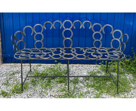 A wrought and forged three seater garden bench formed by an arrangement of horseshoes. 163cm wide. 