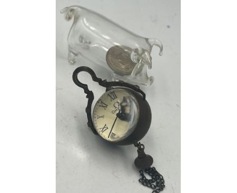 An Omega glass ball clock together with a glass pig with five pence to interior. 
