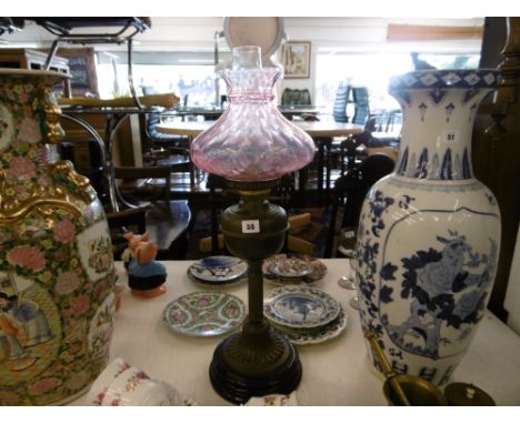 A Victorian oil lamp with cranberry shade
