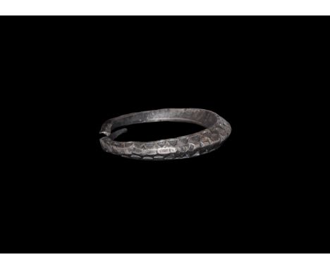 9th-11th century AD. A penannular silver lozenge-section finger ring with tapering finials, two bands of punched triangles to