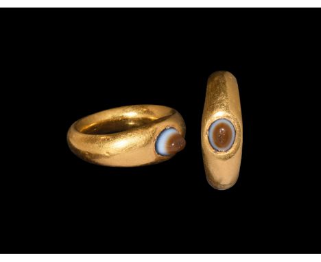 4th-5th century AD. A hollow-formed gold finger ring comprising a broad hoop with expanding shoulders, inset sardonyx cabocho