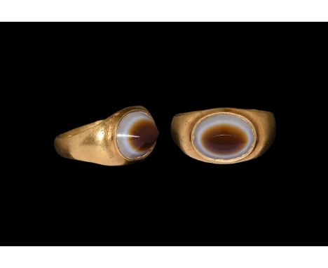 1st-3rd century AD. A gold finger ring with D-section hoop, flared shoulders, plaque with cell and inset banded agate truncat