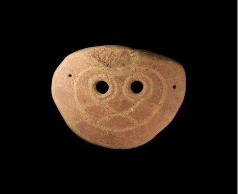 4th-3rd century BC. A slightly domed ceramic funerary(?) mask with two eye-holes and incised intersecting curved lines; attac