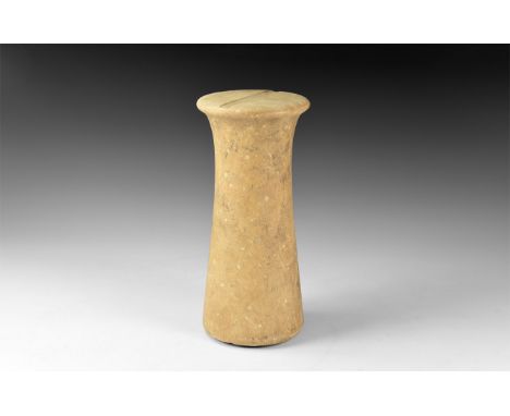 2nd millennium BC. A fossiliferous limestone columnar idol, tapering body with discoid base, shallow slot to each flat face. 