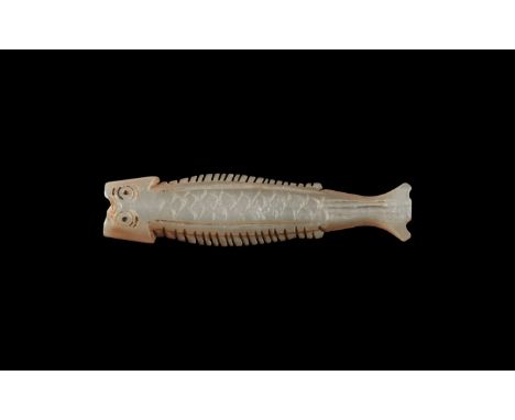 9th-12th century AD. A carved nacre bead of a fish with ring-and-dot eyes, notched lateral fins, scale detailing to the body,