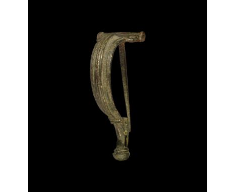 1st century AD. A bronze Aucissa bow brooch with hinged pin, deep bow with median beaded fillet, tapering foot with catch to 