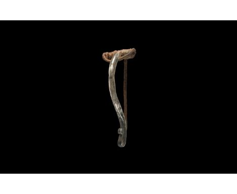 1st century AD. A large silver fibula with D-section bow, scrolled finial with pellet detailing, spring, pin and catch to the