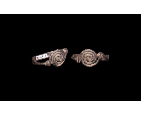 5th-7th century AD. A silver finger ring formed as a flat-section band with wire finials drawn into a whorl with the ends wra