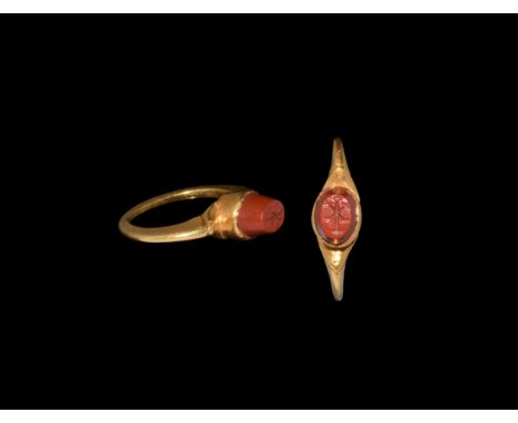 4th century AD. A gold baptismal finger ring with broad flat-section shank, scooped shoulders, central cell with inset red ja