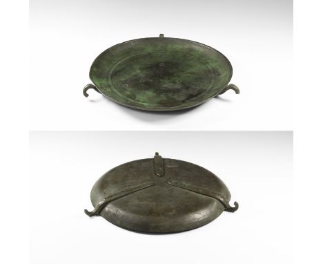 6th-8th century AD. A shallow bronze dished scale-pan with concentric rings, three hooks to the rim with attachment plates, p