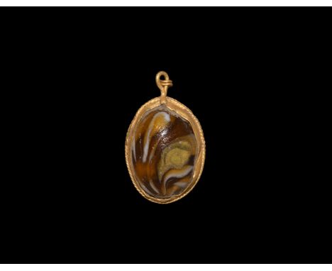 1st-2nd century AD. A gold pendant with suspension loop and link, filigree fillet to the border, inset glass cabochon. See Ru